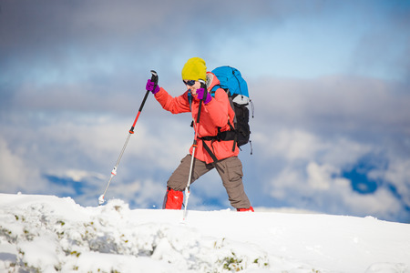girl with backpack walking on snow in the mountains and mountain climbing during the winter holidays.の写真素材