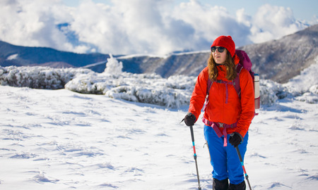 girl with backpack walking on snow in the mountains and mountain climbing during the winter holidays.の写真素材