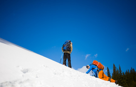 two climbers on a snow slope in the mountains, climbing to the top of the mountain in winter.の写真素材