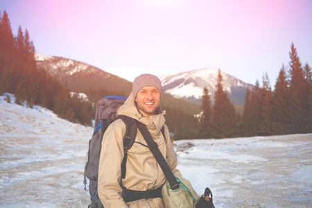 Man with backpack and trekking sticks is photographed on the background of snowy mountains.の写真素材