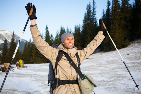 Man with backpack and trekking sticks is photographed on the background of snowy mountains.の写真素材