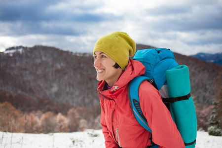 girl with backpack walking on snow in the mountains and mountain climbing during the winter holidays.の写真素材