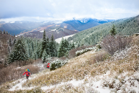Two young women with backpacks climbing a mountain in the winter.の写真素材