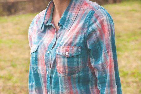 A woman in a plaid shirt blue and pink color against the background of the field.