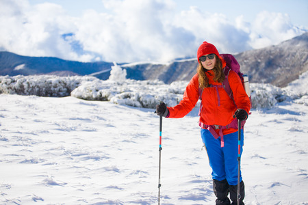girl with backpack walking on snow in the mountains and mountain climbing during the winter holidays.の写真素材