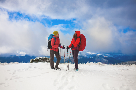 Two friends talk on the background of snow-capped mountain and beautiful sky with cloud.の写真素材