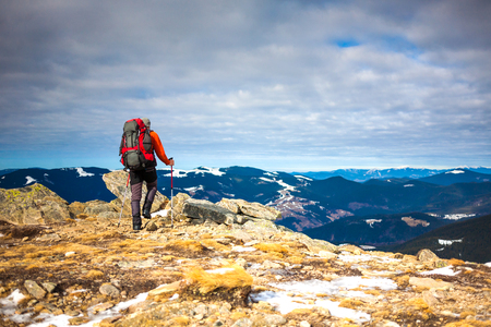 Climber with a backpack on top on a Sunny day, a man with trekking sticks went up on the mountain, people traveling through the beautiful wilderness.の写真素材
