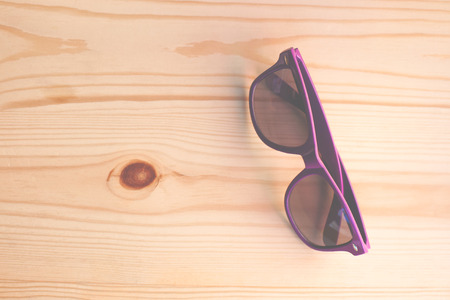Purple sunglasses lying on a wooden table.の写真素材