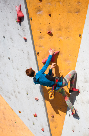 A young woman with short hair climbs on the climbing wall.の写真素材