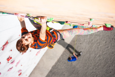 A young woman with short hair climbs on the climbing wall.の写真素材