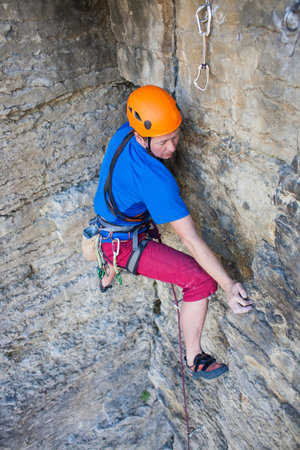 Climber in a helmet climbs to the top of the mountain. Sport activities in nature.