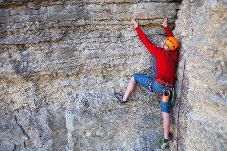 Climber in a helmet climbs to the top of the mountain. Sport activities in nature.