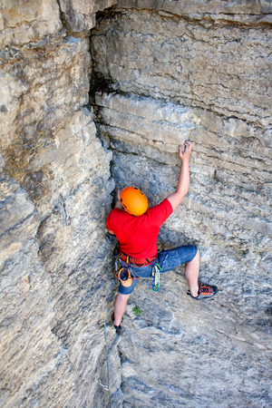 Climber in a helmet climbs to the top of the mountain. Sport activities in nature.の写真素材