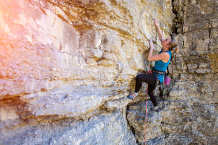 A young woman is climbing on the rocks, active rest on nature.
