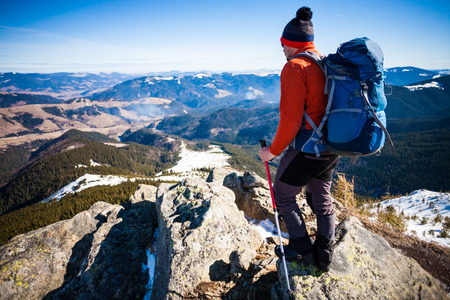 Climber with a backpack on top on a Sunny day, a man with trekking sticks went up on the mountain, people traveling through the beautiful wilderness.の写真素材