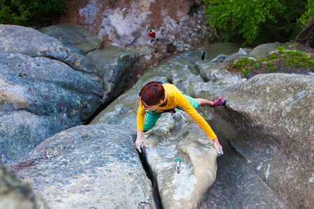 Sports girl climbs on the rock. Climbing in nature, active rest on a day off.の写真素材
