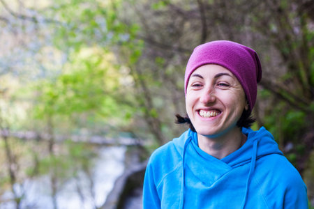 Portrait of a smiling girl on the background of the Park. Girl in sports clothes laughing. Young...