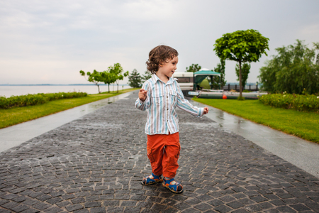 The boy is walking in the park. The child walks along the embankment. The kid walks in the fresh air.の写真素材