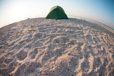 Tent on the sea coast. Camping on a sandy beach. Rest in a deserted place.の写真素材