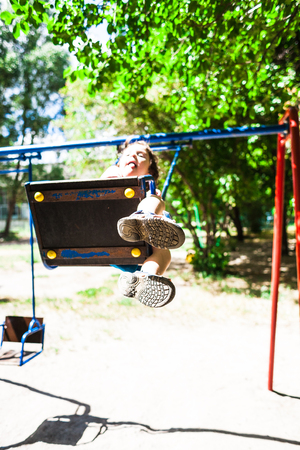The boy is riding on a swing in the amusement park, a happy childhood.の写真素材