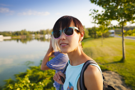 Two friends walking in the park. Girls actively spend time in nature. The women are talking.の写真素材