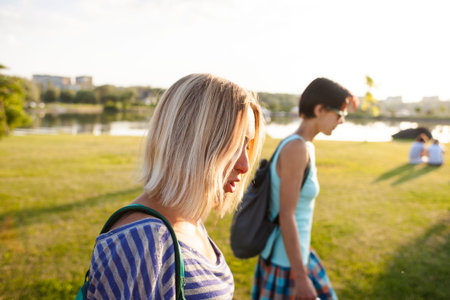 Two friends walking in the park. Girls actively spend time in nature. The women are talking.