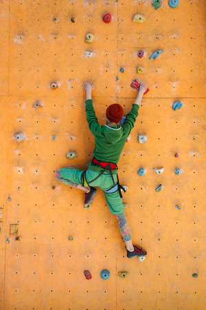 A young woman with short hair climbs on the climbing wall.の写真素材