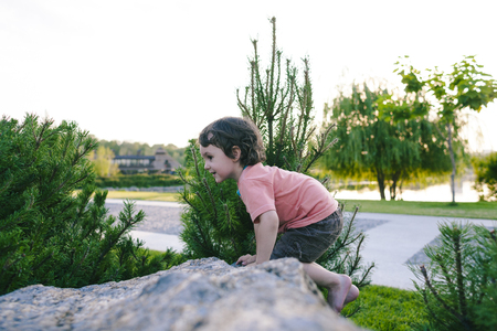 The little boy climbs on the stone. Activity in nature during the holidays. Sport activity.の写真素材
