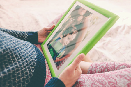 A pregnant woman looks at a photo of a boy. Mom holds a photo frame with a photograph of her son. A small child and memories.の写真素材