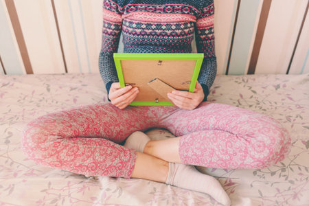 A woman looks at a photo of a boy. Mom holds a photo frame with a photograph of her son. A small child and memories.の写真素材