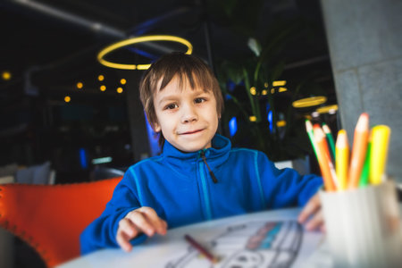 The boy draws with colored pencils. The child paints the picture. Multicolored pencils.