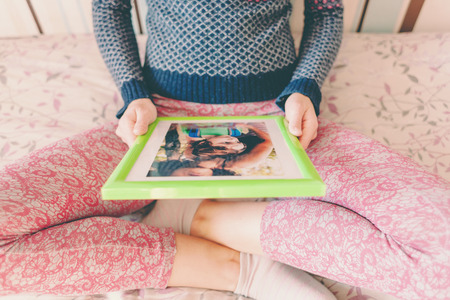 A woman looks at a photo of a boy. Mom holds a photo frame with a photograph of her son. A small child and memories.の写真素材