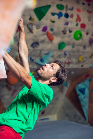 A man climbs on the climbing wall. The climber is training. Extreme sport. Active lifestyle.の写真素材