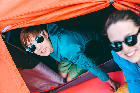 two girls sitting near the tent and have fun talking. Sleeping bag and tent camping.
の写真素材