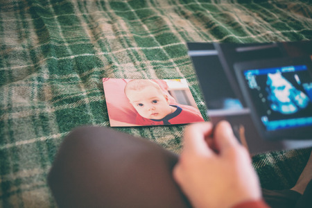 A picture of an ultrasound examination of a pregnant woman. Mom looks at the sonogram. A woman looks at old photos and gives herself up to memories. Old photos.の写真素材