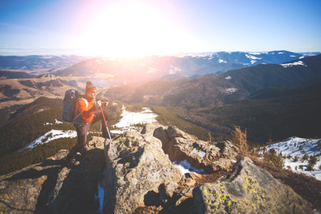 Climber with a backpack on top on a Sunny day, a man with trekking sticks went up on the mountain, people traveling through the beautiful wilderness.の写真素材