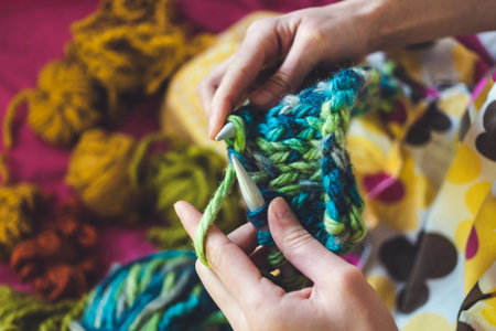 The woman knits. Knitting with knitting needles. Tubes of woolen threads. Multi colored thread. The...