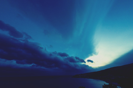 Seaside at sunset. Beautiful seascape at night. Cloudy sky and setting sun. Calm ocean.の写真素材