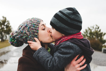 Mom hugs her son in the street. The joy of meeting mother and child. A woman is kissing a boy.の写真素材