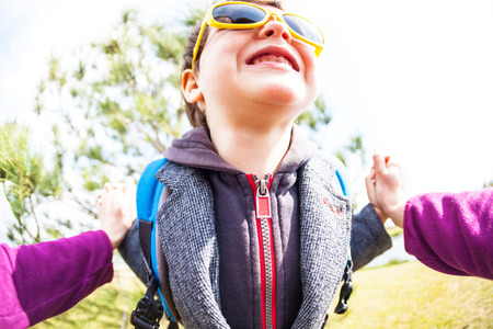A boy in sunglasses plays with his parent. The kid fools around with Mom. A child is having fun outdoors. Fisheye lens. Smiling toddler.の写真素材