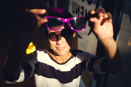 portrait of a smiling girl who holds sunglasses in front of her.