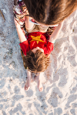 Child with mom on the beach. The boy is playing with his mother. The kid lies on the sand. A woman is resting with her son at the seaside.の写真素材