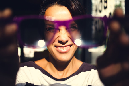 portrait of a smiling girl who holds sunglasses in front of her.の写真素材