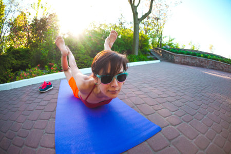 The girl is engaged in yoga in the park. A woman trains on the street. Brunette meditates in nature....