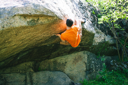 The climber climbs the stone. The athlete is engaged in bouldering. Rock climbing in nature.の写真素材