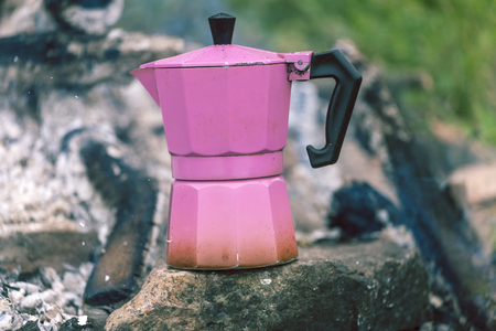 A geyser coffee machine near the fire. Picnic in nature. Camping in the mountains. Morning coffee in the forest.の写真素材