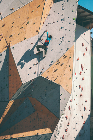 A climber on an artificial relief. A man climbs the climbing wall. Training on a street climbing wall. Preparation for competitions. Workout.の写真素材