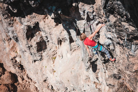 A woman climbs the rock. The athlete trains on a natural relief. Rock climbing in Turkey. A slender girl is engaged in extreme sports. Active hobby. The climber overcomes a difficult route.の写真素材