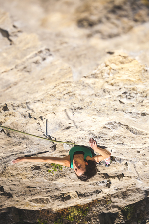 The girl climbs the rock. A woman is engaged in fitness in nature. Extreme sport. Climbing route on natural terrain. Endurance training. Workout.の写真素材
