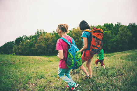 A woman with children goes hiking. Traveling with family. The boy walks with his brother and mother in the forest. Hike with backpacks.のeditorial素材
